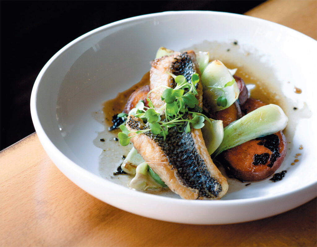 Black Sea Bass with bok choy, glazed sweet potatoes, nori sesame, charred lemon vinaigrette, and micro greens